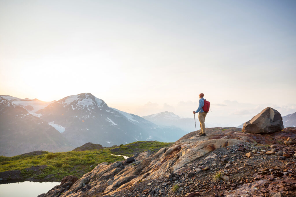 Man on a mountain summit overlooking the landscape, symbolizing hope, freedom, and the FIRE movement to achieve financial independence and retire early.